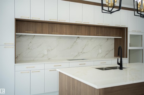Kitchen with two tone color scheme, light stone counters, modern cabinets, tasteful backsplash, and hanging lights - 4006 40 Street, Beaumont, AB - Indoor Photo Showing Other Room