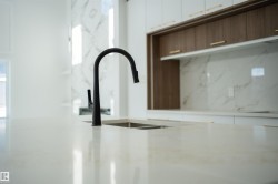 Kitchen view of light stone countertops, backsplash, two tone cabinets, and modern cabinets - 