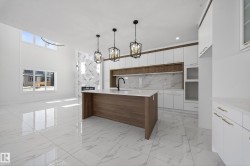 Dual tone kitchen with two tone cabinetry, modern cabinets, light stone countertops, an island with sink, and a kitchen bar - 