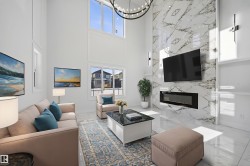 Living room with plenty of natural light, a high ceiling, a high end fireplace, hanging lights, and marble tiled flooring - 