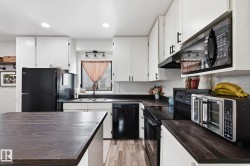 Kitchen featuring black appliances, white cabinets, light wood-style floors, recessed lighting, and a kitchen island - 