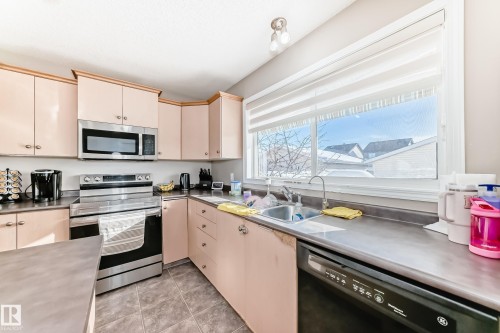 Kitchen featuring stainless steel countertops, stainless steel appliances, and cream cabinetry - 14043 151 Avenue, Edmonton, AB - Indoor Photo Showing Kitchen With Double Sink