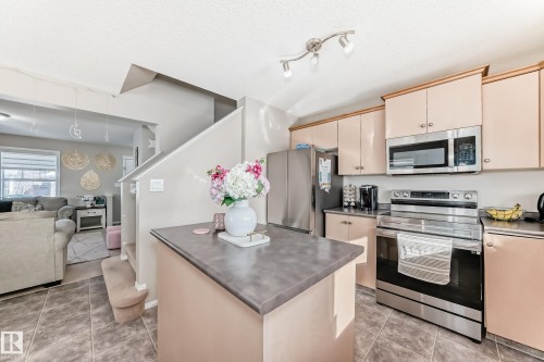 Kitchen with stainless steel appliances, cream cabinets, open floor plan, a center island, and a textured ceiling - 14043 151 Avenue, Edmonton, AB - Indoor Photo Showing Kitchen