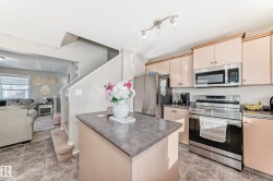 Kitchen with stainless steel appliances, cream cabinets, open floor plan, a center island, and a textured ceiling - 