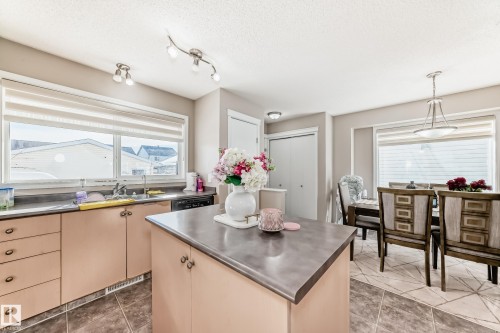 Kitchen with stainless steel counters, healthy amount of natural light, hanging light fixtures, and a textured ceiling - 14043 151 Avenue, Edmonton, AB - Indoor