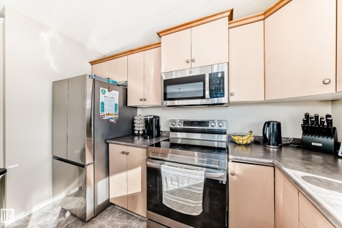 Kitchen with stainless steel appliances, cream cabinets, and a textured ceiling - 14043 151 Avenue, Edmonton, AB - Indoor Photo Showing Kitchen