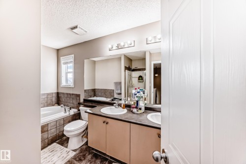 Full bath with double vanity, a garden tub, a textured ceiling, a shower stall, and dark tile patterned flooring - 14043 151 Avenue, Edmonton, AB - Indoor Photo Showing Bathroom