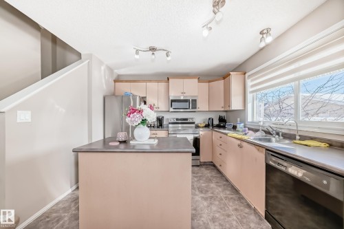 Kitchen with a center island, stainless steel appliances, light wood finish cabinetry, and cream cabinets - 14043 151 Avenue, Edmonton, AB - Indoor Photo Showing Kitchen With Double Sink