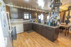 Kitchen with a peninsula, white appliances, light wood-style floors, light countertops, and dark wood finish cabinetry - 