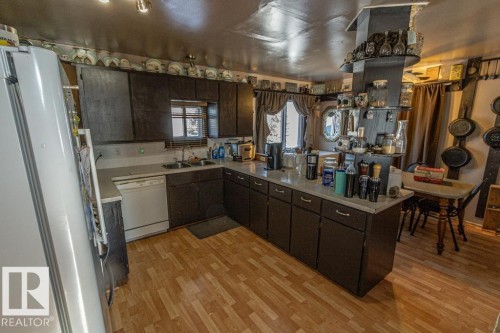 Kitchen with refrigerator, a peninsula, dark wood finish cabinets, white dishwasher, and light wood-type flooring - 11126 Twp Rd 605A, Rural St. Paul County, AB - Indoor Photo Showing Kitchen With Double Sink
