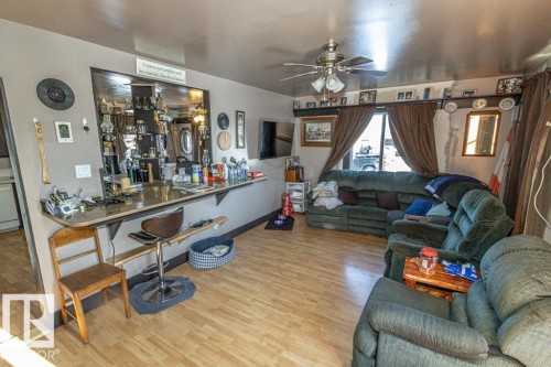 Living room with wood finished floors, a ceiling fan, and bar - 11126 Twp Rd 605A, Rural St. Paul County, AB - Indoor