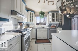 Kitchen featuring stainless steel appliances, glass insert cabinets, light countertops, and tasteful backsplash - 