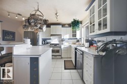 Kitchen featuring glass insert cabinets, white cabinetry, a breakfast bar, a center island, and stainless steel appliances - 