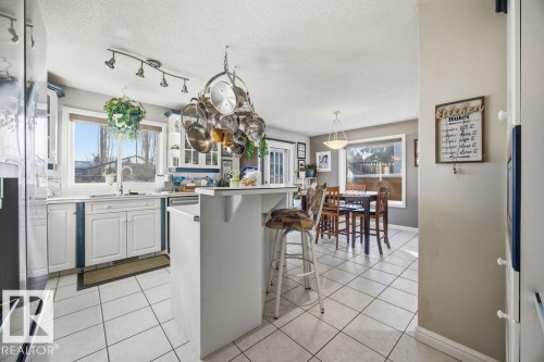 Kitchen with white cabinetry, high quality fridge, light countertops, a kitchen bar, and light tile patterned floors - 3011 44A Street, Edmonton, AB - Indoor