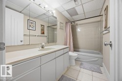 Bathroom with vanity, shower / bath combination with curtain, light tile patterned floors, and a drop ceiling - 