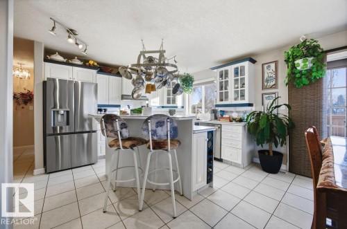 Kitchen featuring a kitchen breakfast bar, white cabinetry, stainless steel appliances, a center island, and light countertops - 3011 44A Street, Edmonton, AB - Indoor