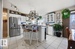 Kitchen featuring a kitchen breakfast bar, white cabinetry, stainless steel appliances, a center island, and light countertops - 