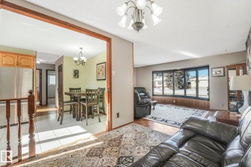 Living room with a chandelier, a textured ceiling, and light tile patterned floors - 760 Knottwood Road S, Edmonton, AB - Indoor