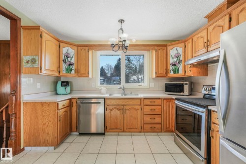 Kitchen featuring stainless steel appliances, light countertops, a chandelier, decorative backsplash, and a textured ceiling - 760 Knottwood Road S, Edmonton, AB - Indoor Photo Showing Kitchen