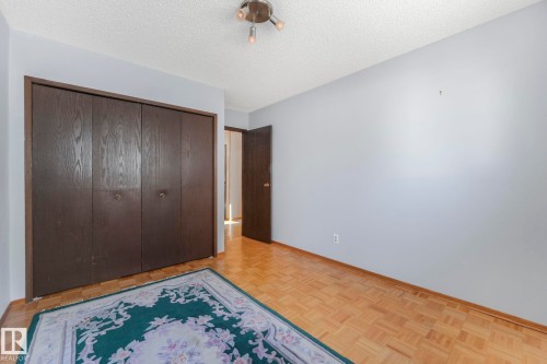 Unfurnished bedroom featuring a textured ceiling, a closet, and parquet floors - 760 Knottwood Road S, Edmonton, AB - Indoor Photo Showing Other Room