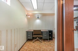 Office area with a drop ceiling, wallpapered walls, and parquet flooring - 