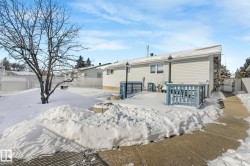 Snow covered back of property featuring a fenced backyard and a wooden deck - 