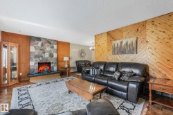 Living area featuring wooden walls, parquet flooring, a textured ceiling, and a fireplace - 