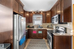 Kitchen with stainless steel appliances, light countertops, tasteful backsplash, dark wood finish cabinets, and light tile patterned floors - 