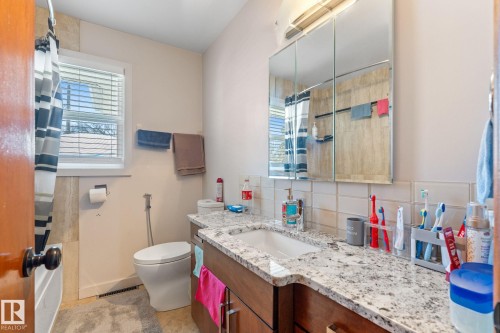 Full bathroom with a shower with shower curtain, vanity, tasteful backsplash, and light tile patterned floors - 9847 79 Street, Edmonton, AB - Indoor Photo Showing Bathroom