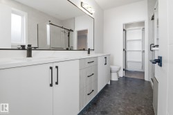 Full bathroom with a shower stall, double vanity, dark flooring, and a spacious closet - 