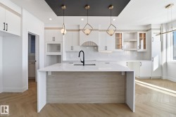Kitchen featuring parquet floors, pendant lighting, light stone countertops, and white cabinets - 