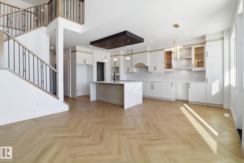 Kitchen with hanging light fixtures, parquet floors, modern cabinets, a breakfast bar, and two tone color scheme - 90 Eldridge Point(E), St. Albert, AB - Indoor Photo Showing Kitchen