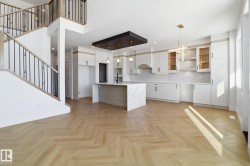 Kitchen with hanging light fixtures, parquet floors, modern cabinets, a breakfast bar, and two tone color scheme - 