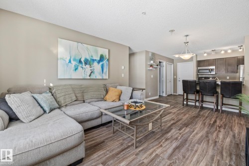 Living room featuring dark wood-type flooring and a textured ceiling - 109 5370 Chappelle Road, Edmonton, AB - Indoor Photo Showing Living Room