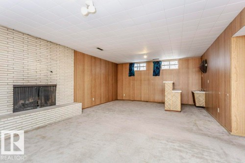 Basement featuring a brick fireplace, light colored carpet, and wooden walls - 6304 131 Street, Edmonton, AB - Indoor Photo Showing Basement