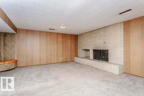 Unfurnished living room with wooden walls, a brick fireplace, and light carpet - 6304 131 Street, Edmonton, AB - Indoor Photo Showing Other Room