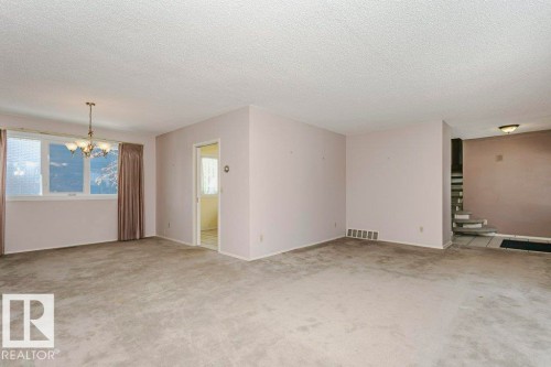 Empty room featuring a chandelier, light colored carpet, and a textured ceiling - 6304 131 Street, Edmonton, AB - Indoor Photo Showing Other Room
