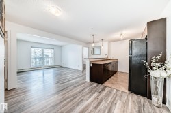 Kitchen with pendant lighting, open floor plan, black appliances, baseboard heating, and a peninsula - 