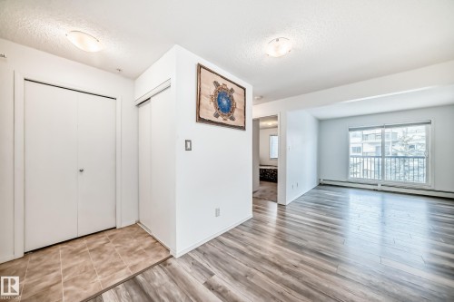 Foyer entrance with a textured ceiling, a baseboard heating unit, and wood finished floors - 306 1188 Hyndman Road, Edmonton, AB - Indoor Photo Showing Other Room