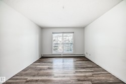 Empty room with wood finished floors, baseboard heating, and a textured ceiling - 