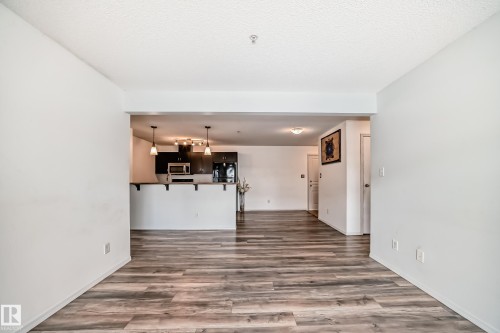 Unfurnished living room with dark wood-style floors and a textured ceiling - 306 1188 Hyndman Road, Edmonton, AB - Indoor Photo Showing Other Room