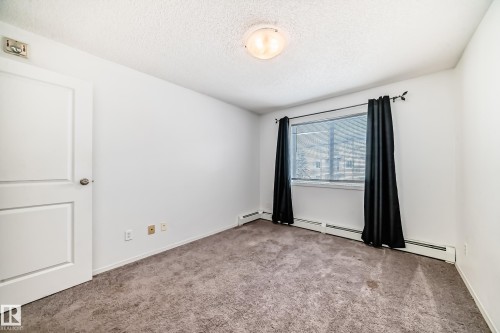 Unfurnished room with light carpet, a textured ceiling, and baseboard heating - 306 1188 Hyndman Road, Edmonton, AB - Indoor Photo Showing Other Room