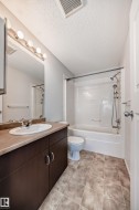 Bathroom featuring vanity, a textured ceiling, bathing tub / shower combination, and light tile patterned floors - 