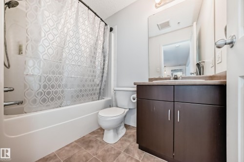 Bathroom featuring shower / bath combo, vanity, and light tile patterned flooring - 306 1188 Hyndman Road, Edmonton, AB - Indoor Photo Showing Bathroom