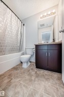Bathroom featuring vanity, shower / tub combo with curtain, light tile patterned flooring, and a textured ceiling - 