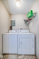 Laundry area featuring electric panel, a textured ceiling, and separate washer and dryer - 