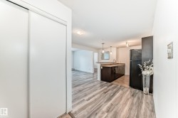 Kitchen featuring hanging light fixtures, black appliances, light wood-style flooring, a peninsula, and open floor plan - 