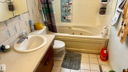 Full bathroom featuring backsplash, vanity, a combined bath / shower with jetted tub, tile walls, and light tile patterned floors - 