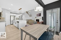 View from dining area into the kitchen, the expansive open-to-below great room, and grand open staircase up to the second level. - 