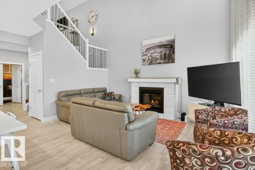 Beautiful open-to-below great room with 18' ceilings, large, bright windows, and a cozy feature gas fireplace. - 1909 Davidson Wynd, Edmonton, AB - Indoor With Fireplace